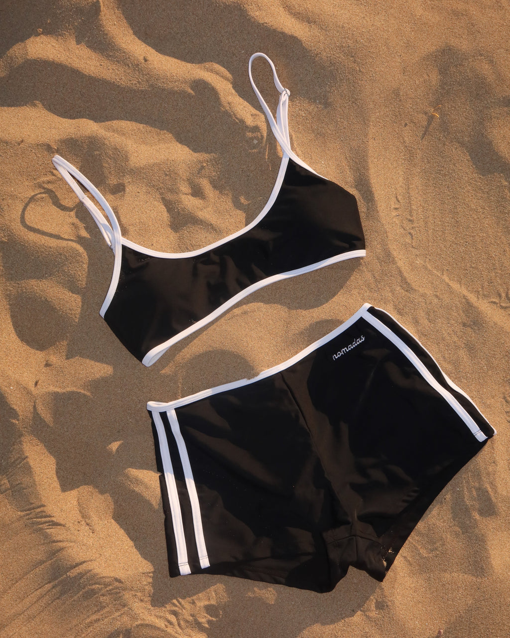 Black swim trunks with white trim on a sandy surface